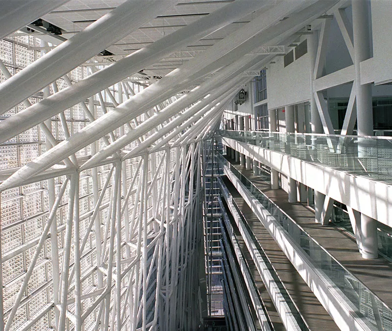 Vue intérieure d’un édifice avec des colonnes blanches, plusieurs fenêtres et les coursives.